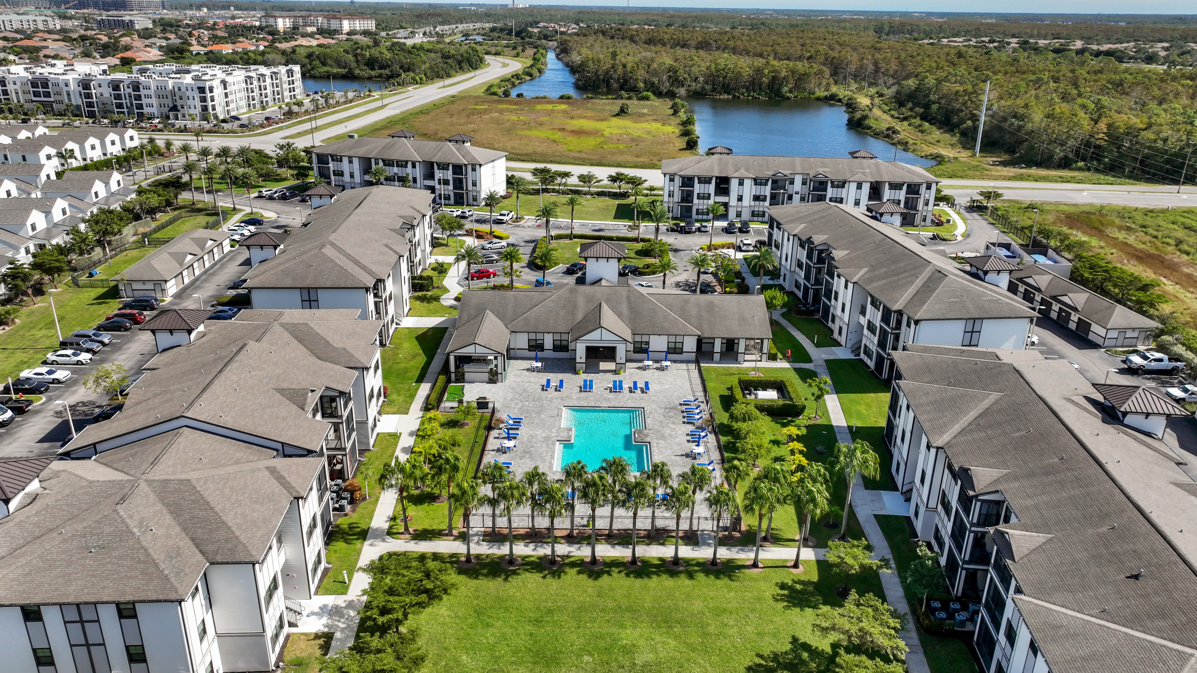 An aerial view of a resort with a swimming pool and palm trees.